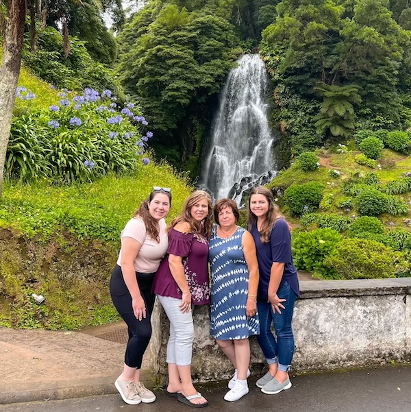 Elaina with her mom, grandma, and aunt in front of a waterfall in the Azores