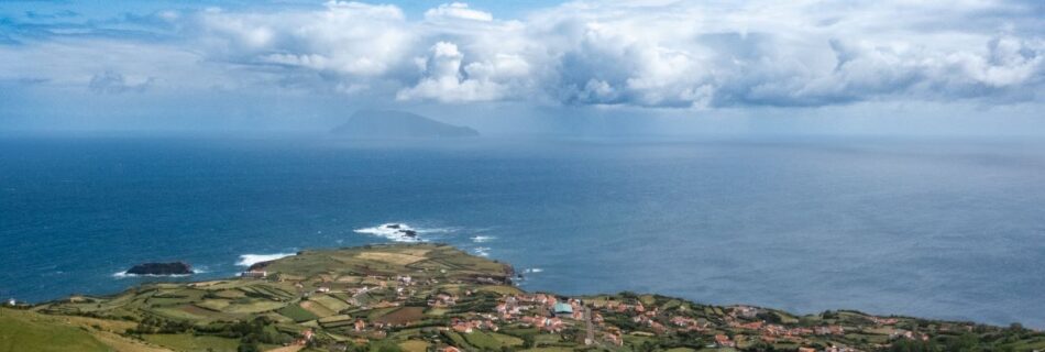 View over a small village on Flores island looking out at Corvo island in the distance