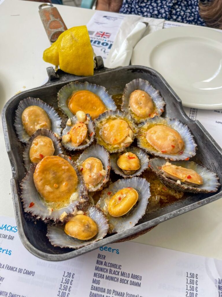 Grilled Lapas (limpets) in a pan with half a lemon 