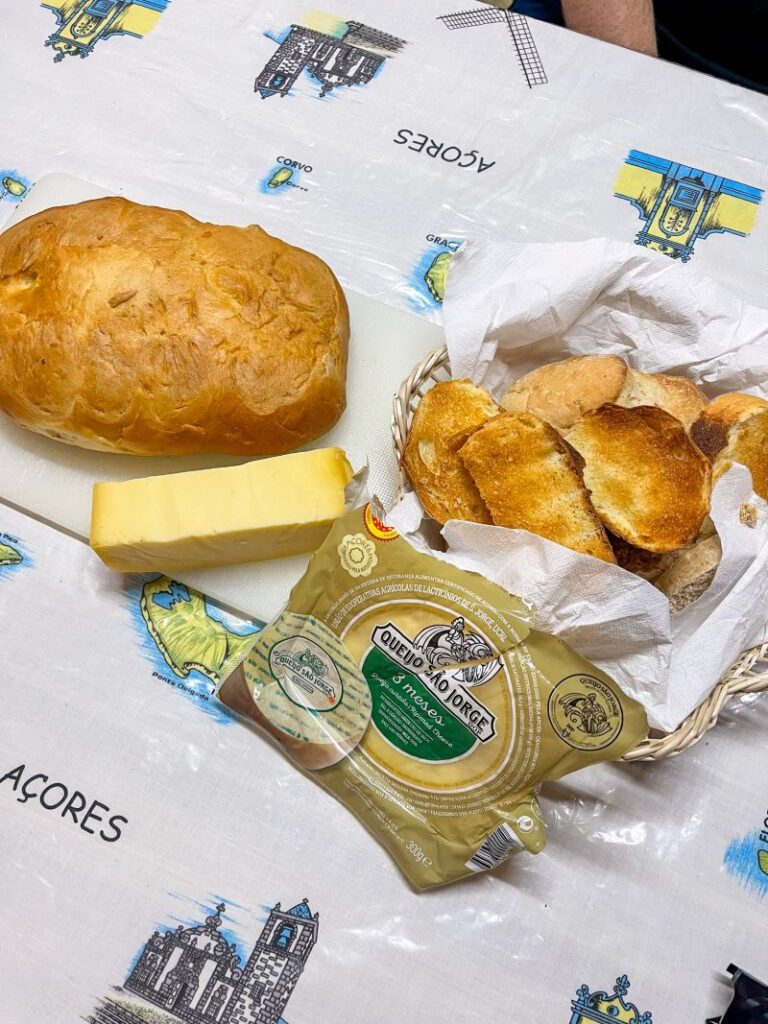 Loaf of sweet bread with some Queijo Sao Jorge and a basket of toast.