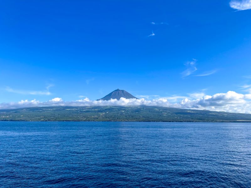 A view of Mount Pico and the island of Pico itself from the inter-island ferry. Mount Pico is sticking up over a low layer of clouds.